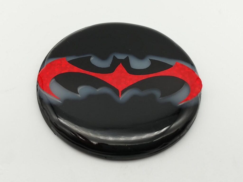 Batman and Robin emblem - black PETG background with sparkly silver and a white haze epoxy, glitter black and sparkly red vinyl